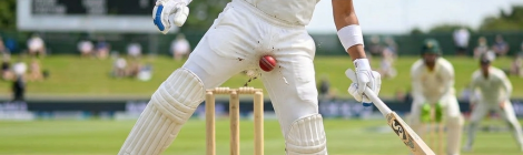 Cricket batsman diving forward to strike the ball near stumps